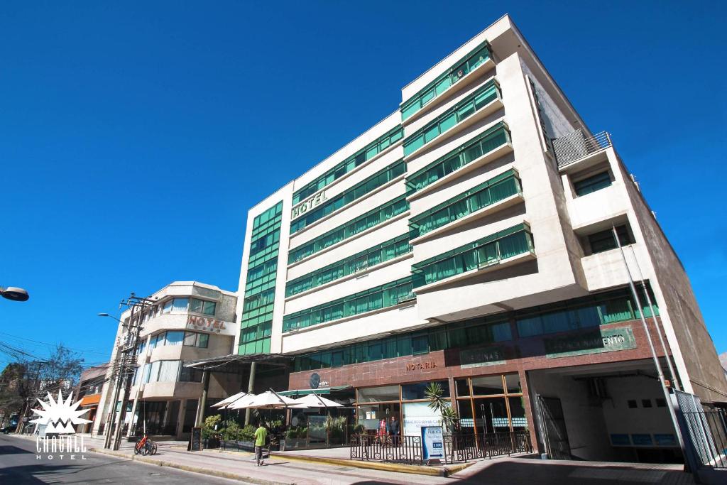 un grand bâtiment dans une rue de la ville avec des gens qui marchent devant dans l'établissement Hotel Chagall, à Copiapó