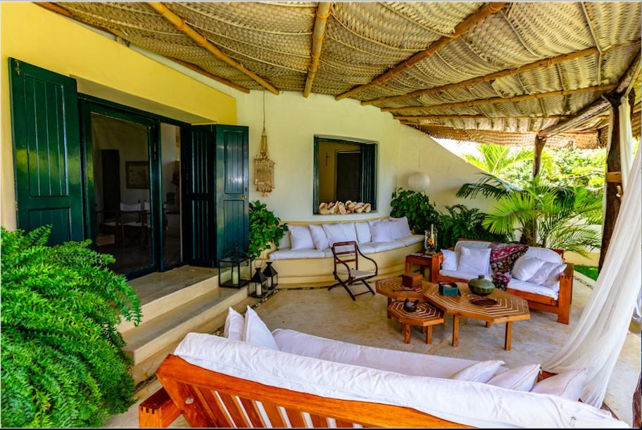 una sala de estar al aire libre con sofás y mesas blancos. en Casa La Ciprea, en Máncora