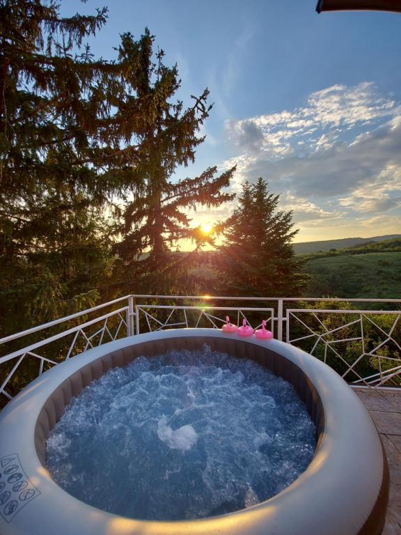 una bañera de hidromasaje en una terraza con vistas a la puesta de sol en el fondo en Lux Star-vila za odmor en Bešenovački Prnjavor