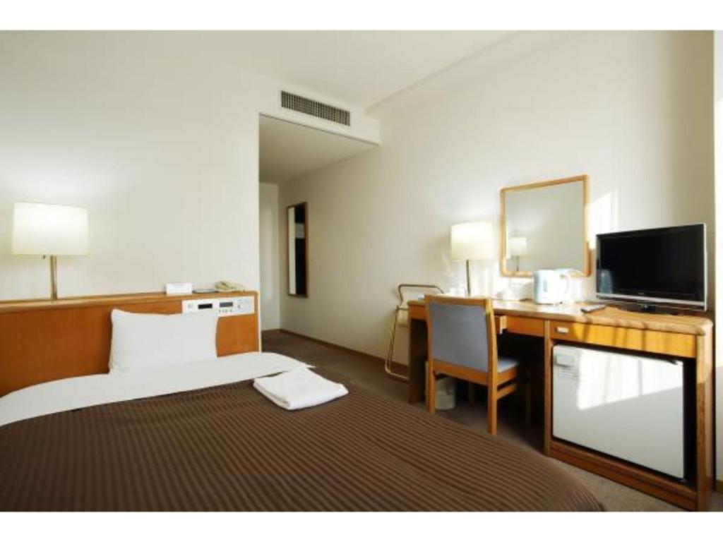 SAIDAIJI GRAND HOTEL - Vacation STAY 92837 في أوكاياما: غرفة في الفندق بها سرير ومكتب وبه جهاز كمبيوتر