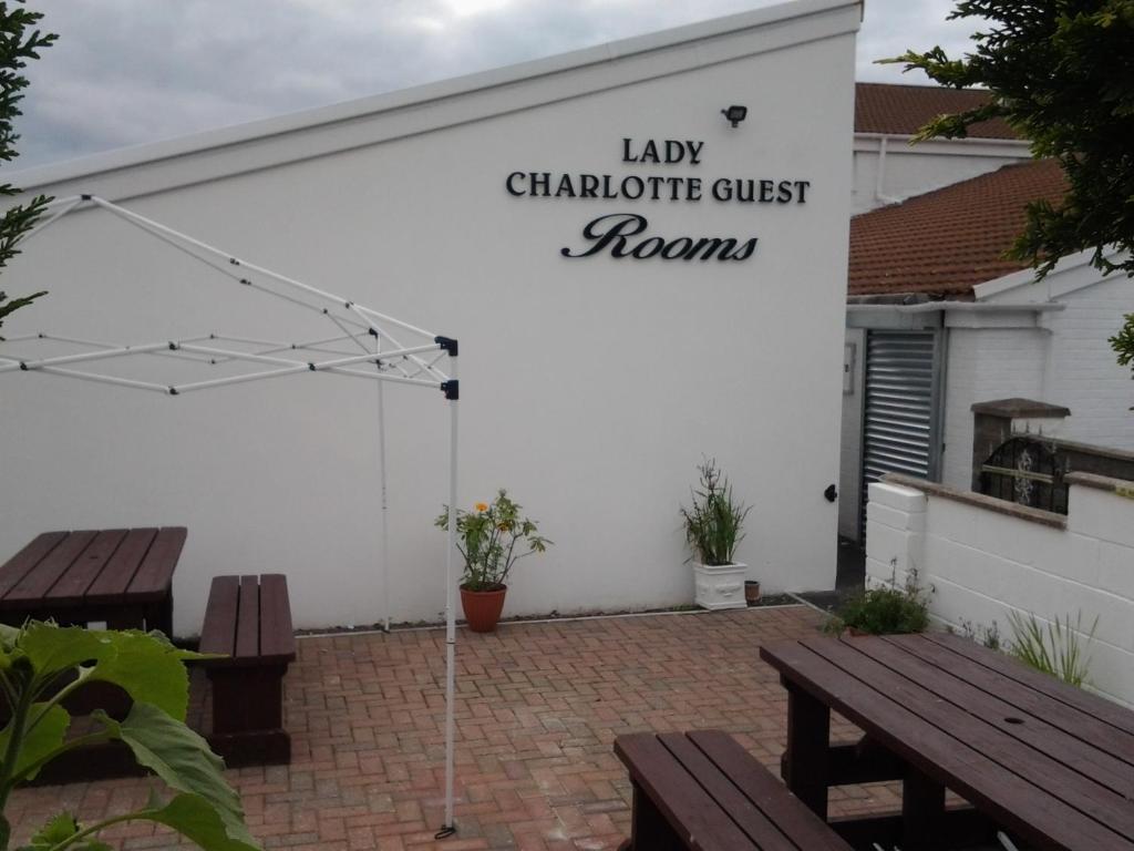Lady Charlotte Guest rooms triple rooms في Dowlais: كراج أبيض مع مقاعد وإشارة تشير إلى غرف ضيوف السيدة chiropract