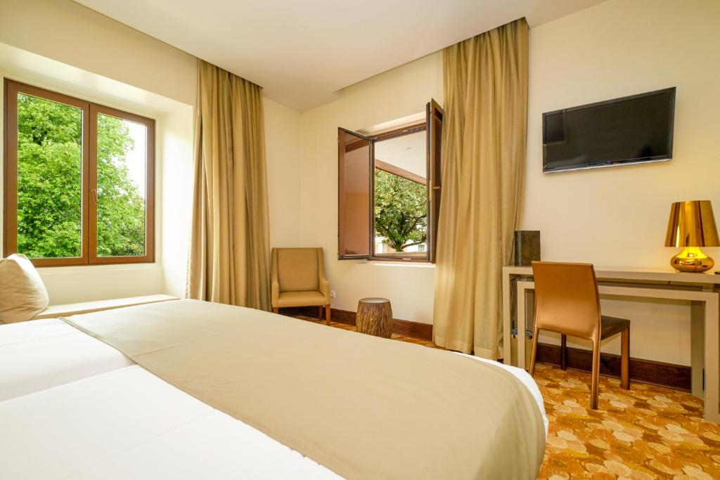a hotel room with a bed and a desk and windows at Sintra Boutique Hotel in Sintra