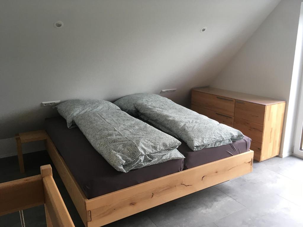 una cama de madera con 2 almohadas encima en Zeitfrei-Apartments en Kirchheim unter Teck