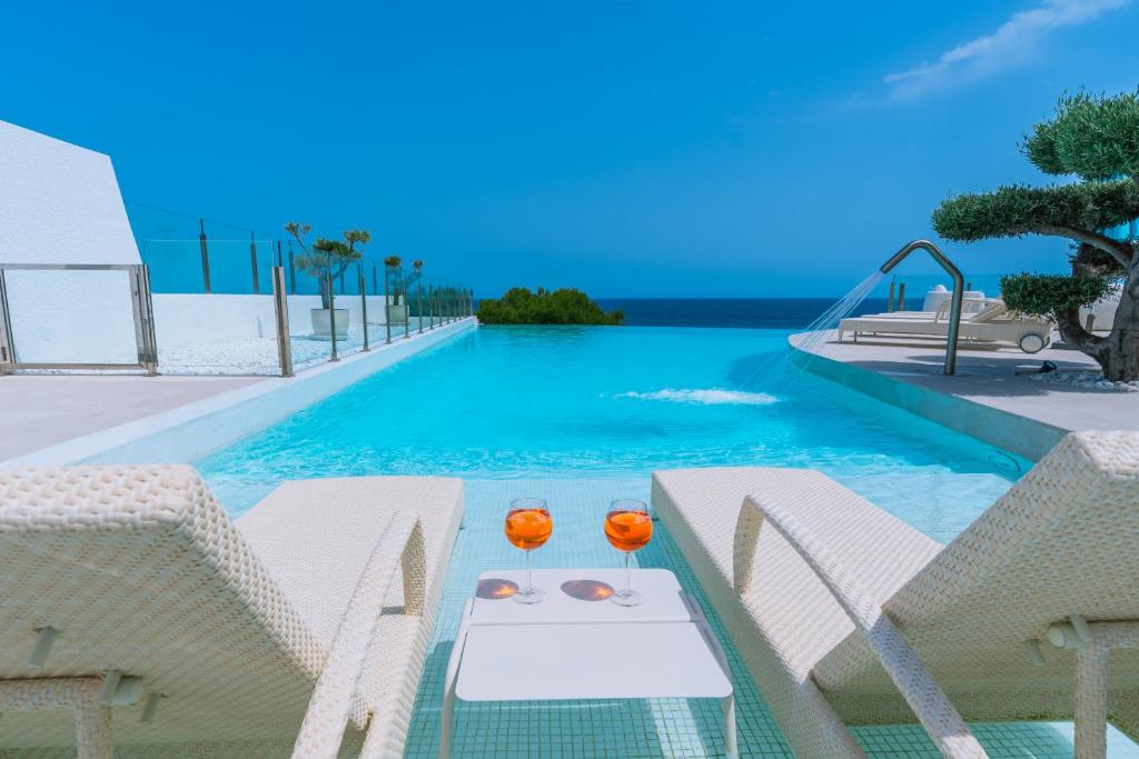 a pool with chairs and a table with two glasses at Maryvilla Inspiracion y Vacaciones - Grand Villa Penon in Calpe
