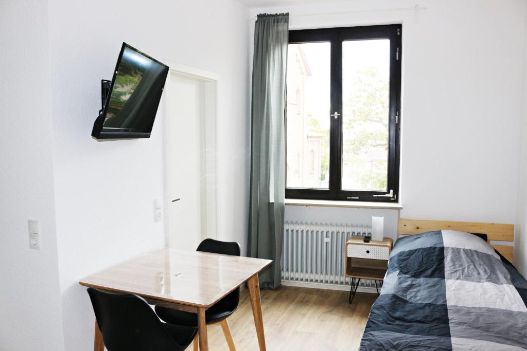 Schlafzimmer mit einem Bett, einem Tisch und einem TV in der Unterkunft Fewo am Museum in Schifferstadt