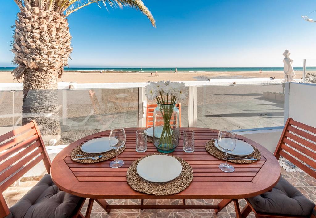 a wooden table with plates and glasses on the beach at Luxury Suite Sea Front II in Playa Honda
