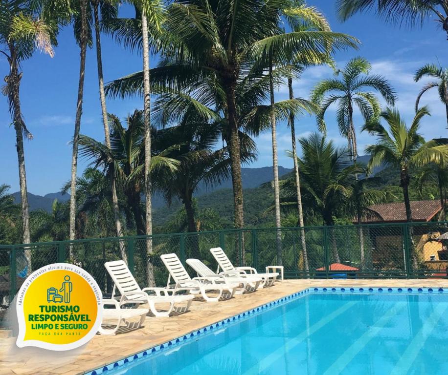 a swimming pool with lounge chairs and palm trees at Marencanto Pousada in Ubatuba