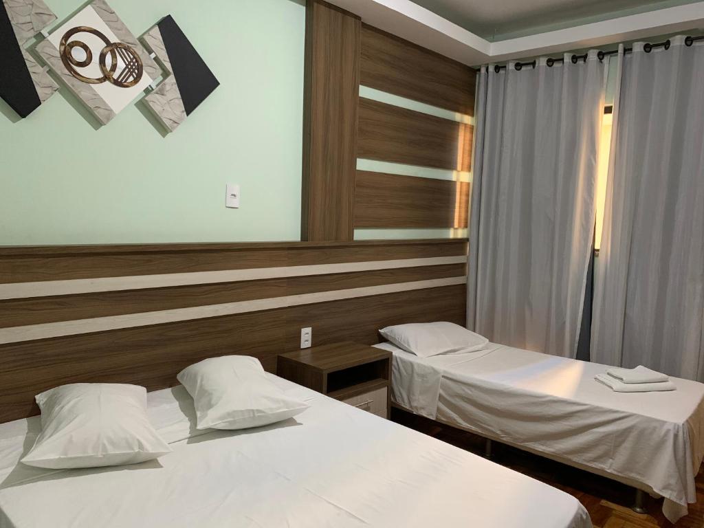 a hotel room with two beds and a mirror at Hotel Glória Barbacena in Barbacena