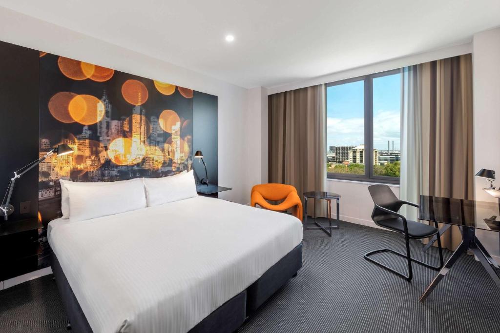 a hotel room with a large bed and a large window at Radisson On Flagstaff Gardens Melbourne in Melbourne