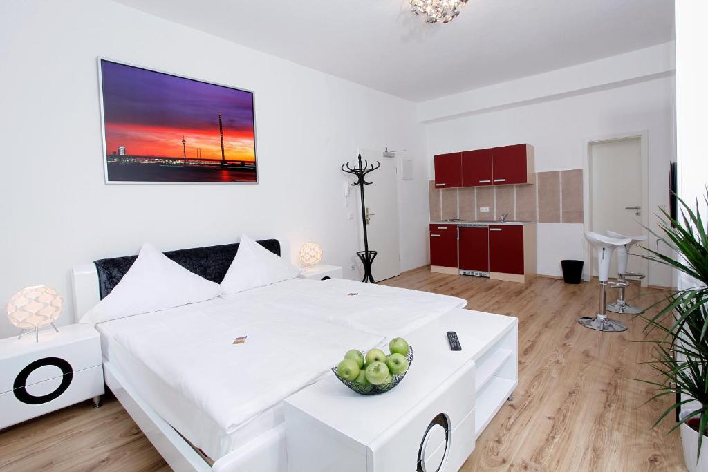 a white bedroom with a large white bed with a bowl of fruit at Hotel Design Apart in Düsseldorf