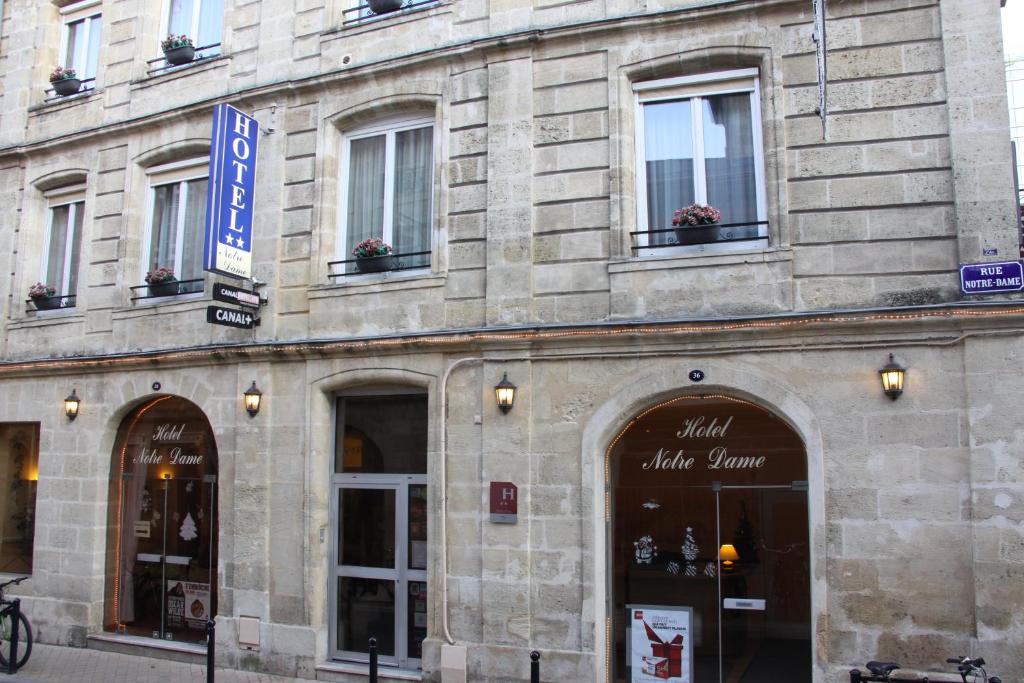 a large stone building with windows on a street at Hôtel Notre Dame in Bordeaux