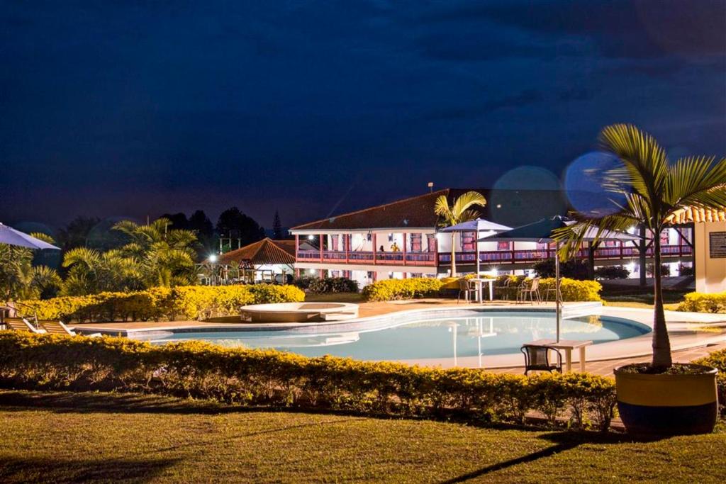 a swimming pool in front of a resort at night at Hotel Arrayanes del Quindío in Montenegro