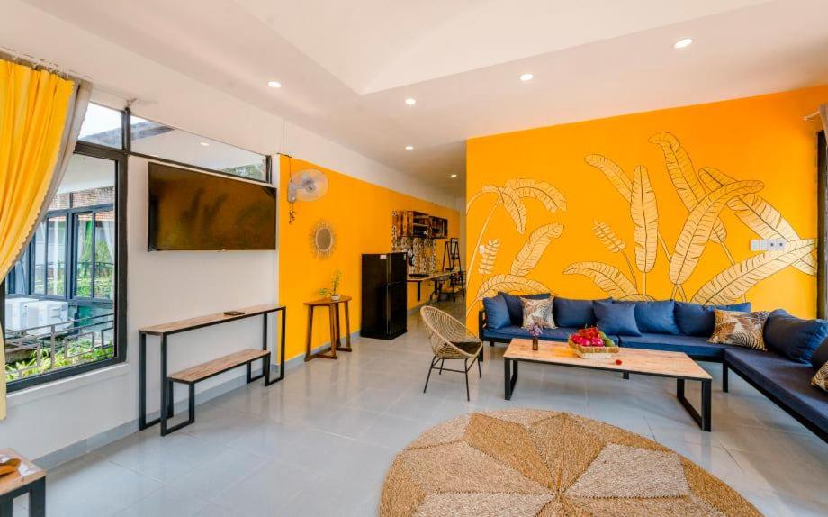 a living room with a blue couch and a yellow wall at Homestay Vườn Pháp II in Buon Ma Thuot