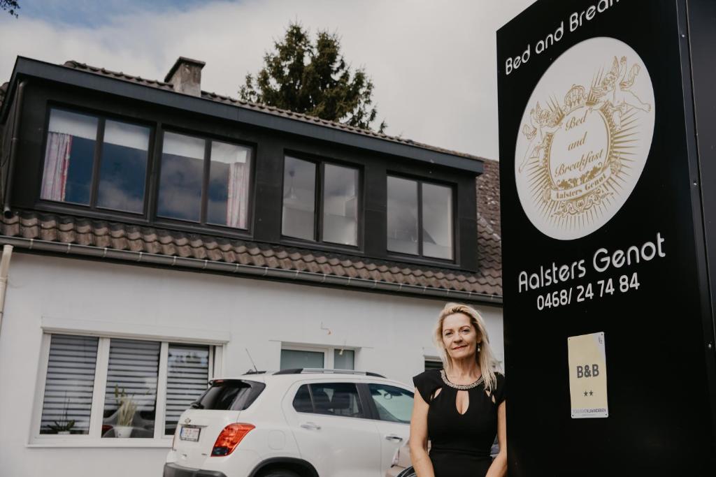 une femme debout à côté d'un panneau devant un bâtiment dans l'établissement B&B Aalsters genot, à Aalst