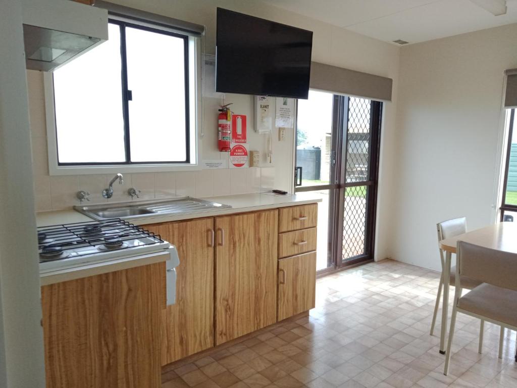 a kitchen with a sink and a stove top oven at Lang Lang Caravan Park 