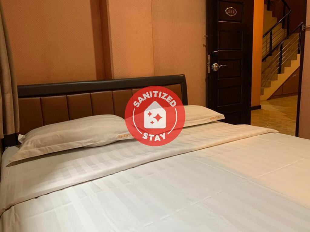 un letto con un cartello rosso sopra di Hotel Rumah Shinta a Giacarta