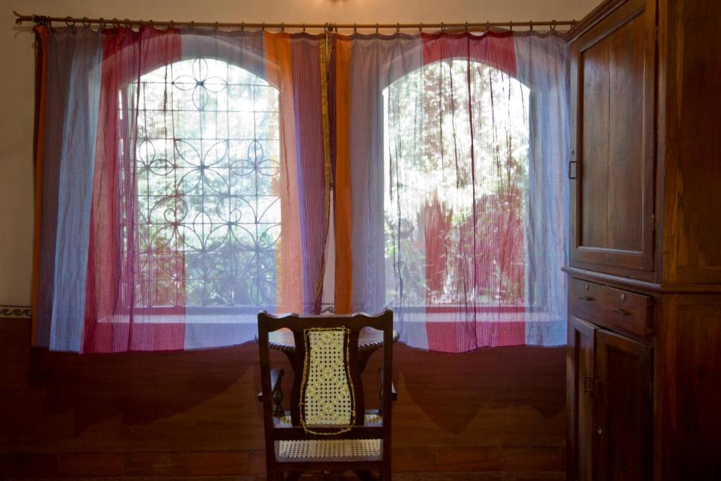 a chair sitting in front of two windows at Bhakti Kutir in Palolem
