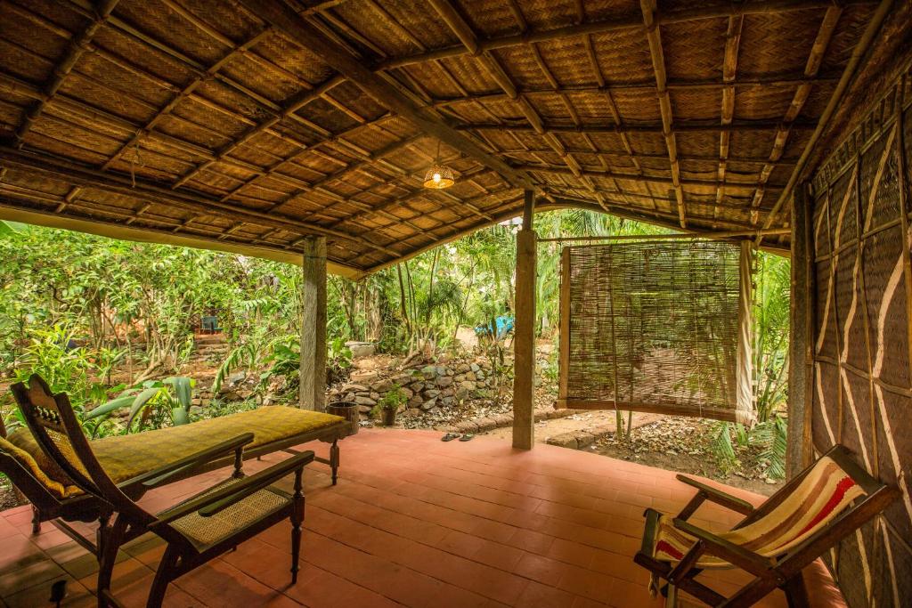 a porch with two chairs and a bird cage at Bhakti Kutir in Palolem