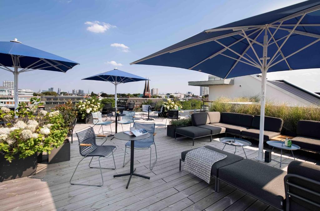 un patio con mesas, sillas y sombrillas en la azotea en OBERDECK Studio Apartments - Adults only, en Hamburgo