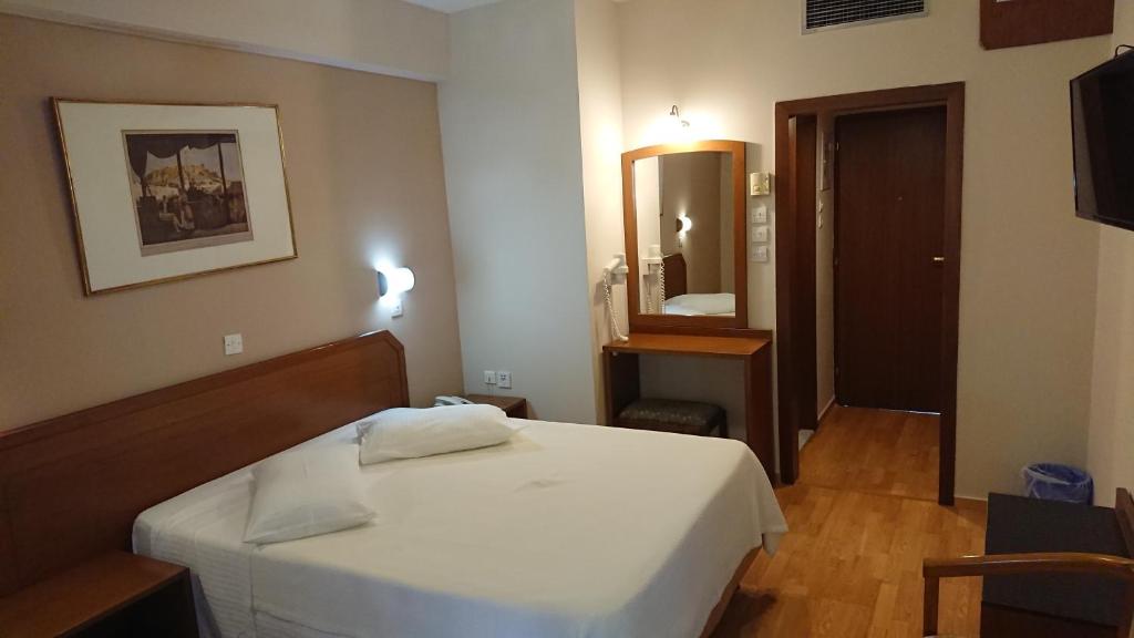 una camera con letto bianco e specchio di Economy Hotel ad Atene