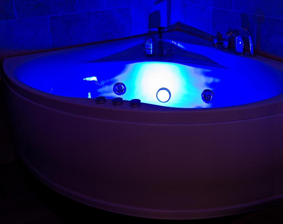a bathroom with a blue tub in a dark room at L’Emmaline in Chambéry