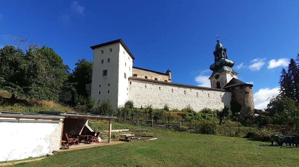 a large white building with a clock tower on a hill at Hostel Skautský dom in Banská Štiavnica