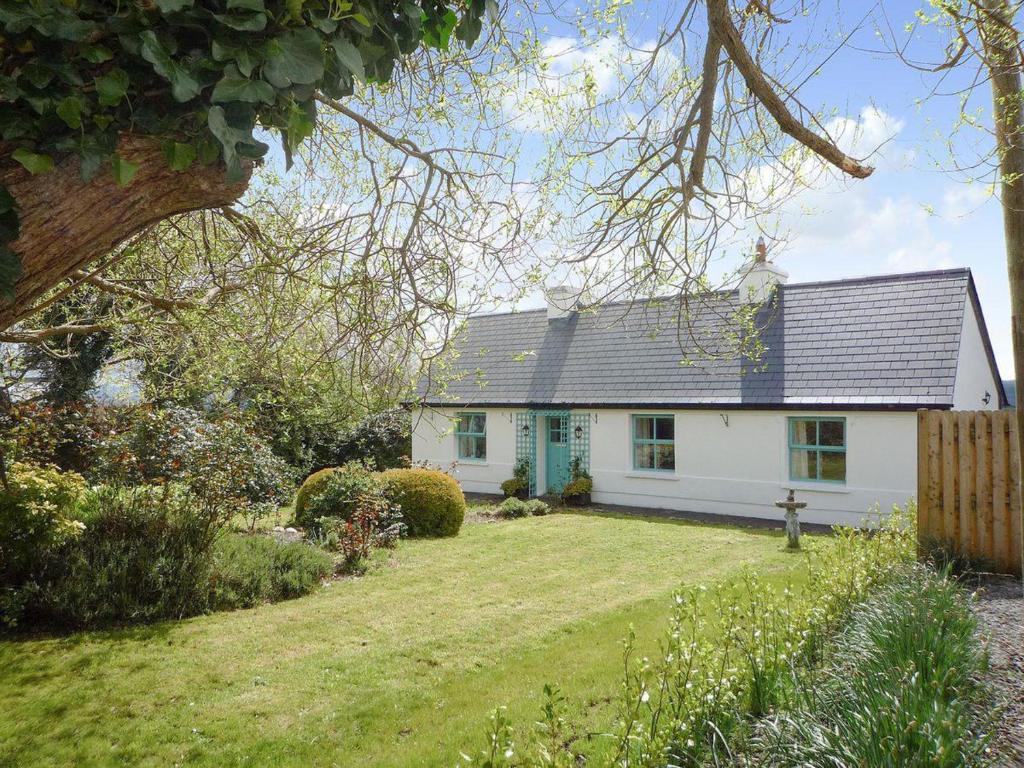 基洛格林的住宿－Fleur Cottage Killorglin by Trident Holiday Homes，蓝色屋顶和庭院的白色房子