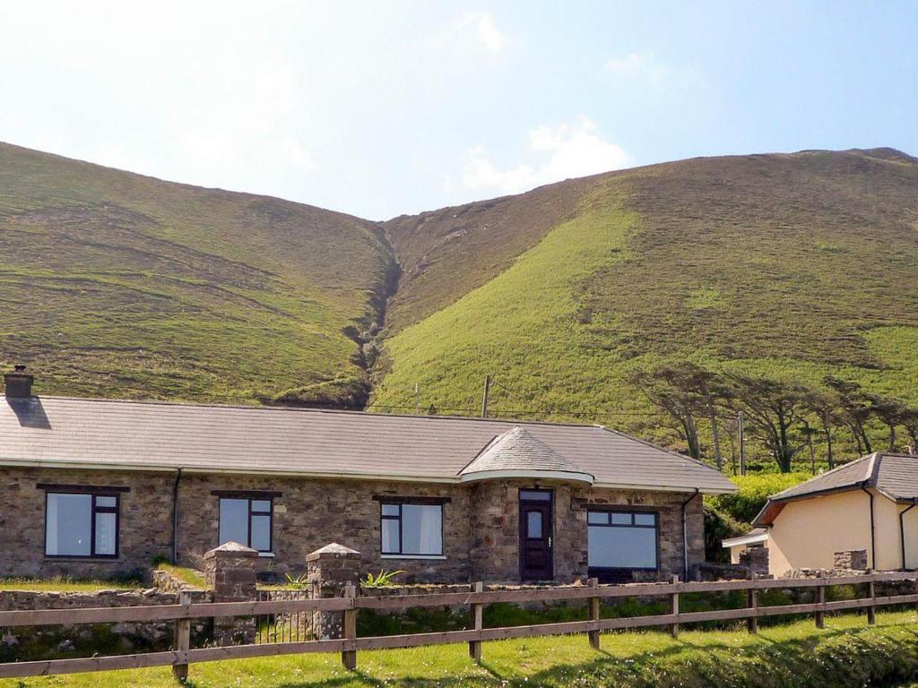 una casa de piedra frente a una montaña en The Lodge Rossbeigh by Trident Holiday Homes en Glenbeigh