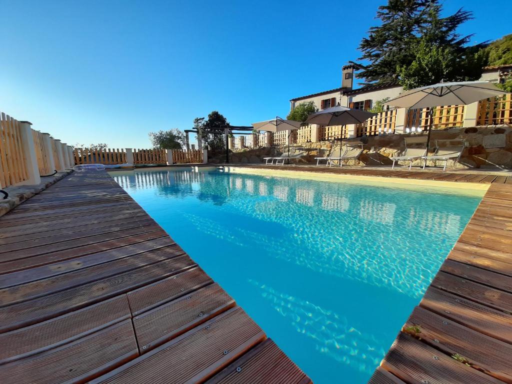 a swimming pool with a wooden deck and blue water at Fonte di Zeno in Marciana
