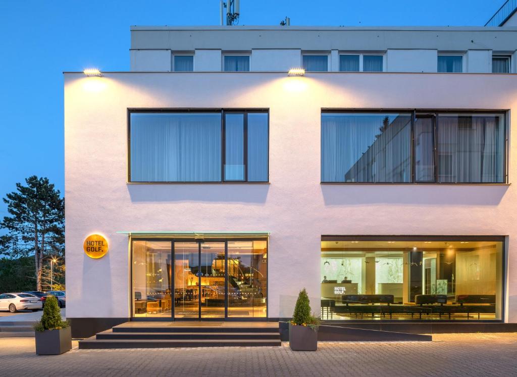eine Fassade eines weißen Gebäudes mit großen Fenstern in der Unterkunft Hotel Golf Prague in Prag