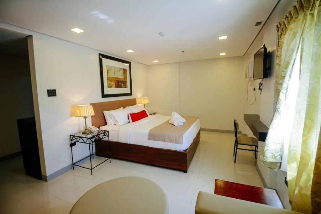 Habitación de hotel con cama y TV en Belltower CSheLi Suites, en Vigan
