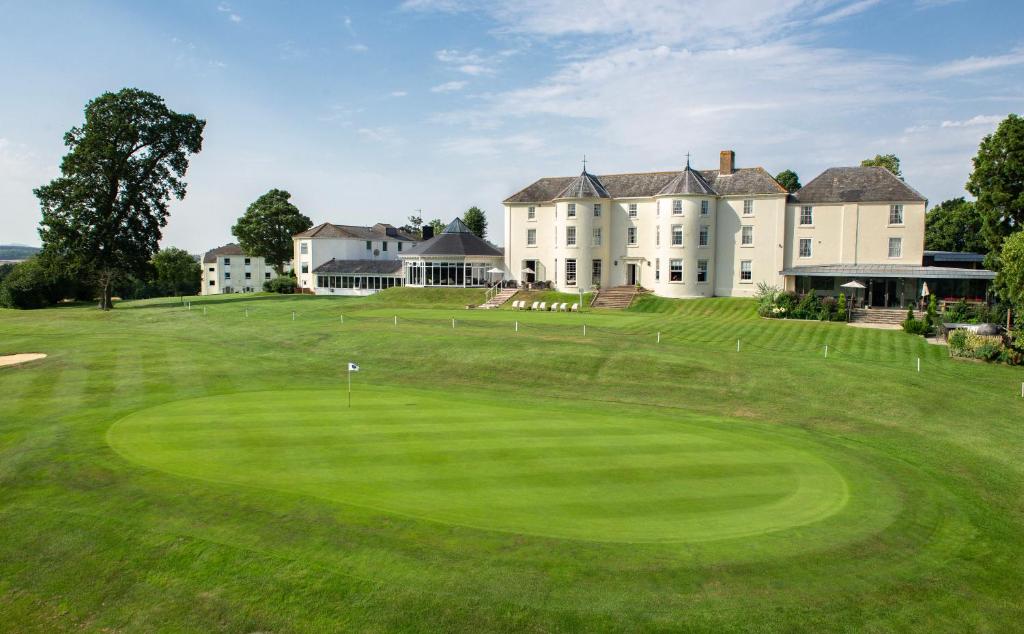 a view of a large house with a green yard at Tewkesbury Park in Tewkesbury