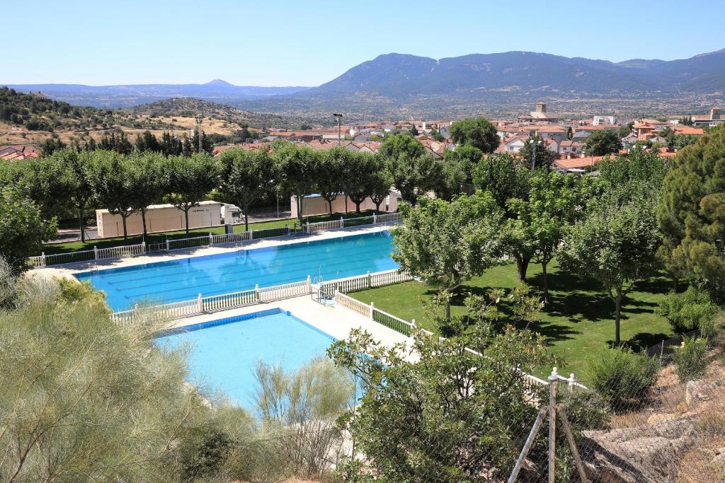 a swimming pool with trees and a city in the background at Apartamento Abuela Benita in Cebreros