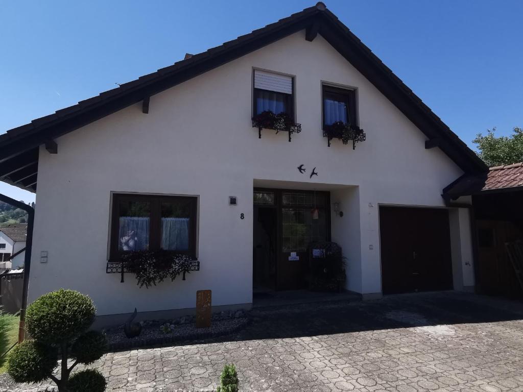 a white house with two windows and a driveway at Haus am Mühlbach in Wilhelmsdorf