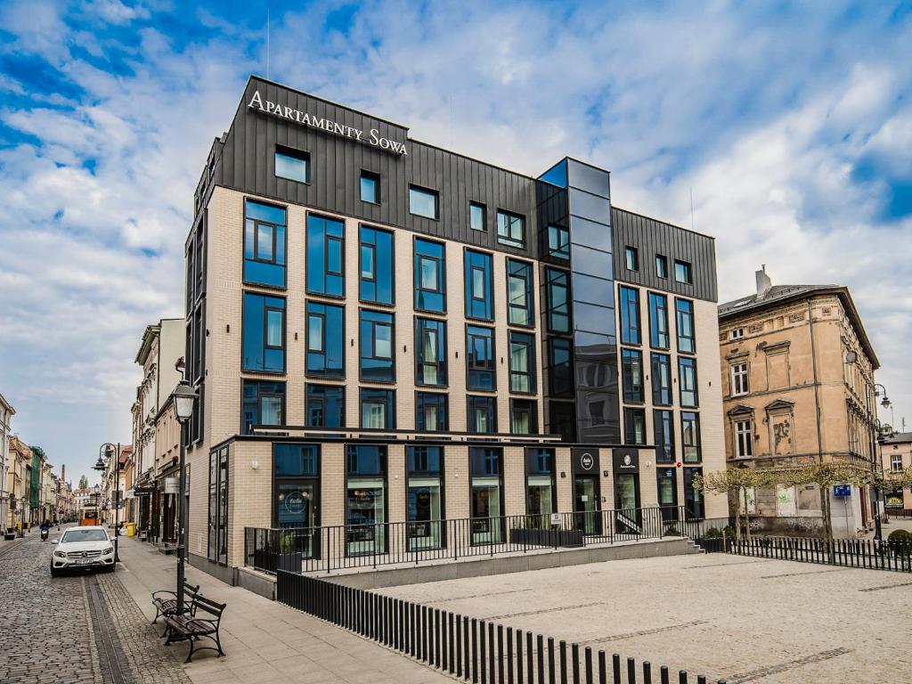 a large building on a city street with a fence at Apartamenty Sowa Bydgoszcz in Bydgoszcz