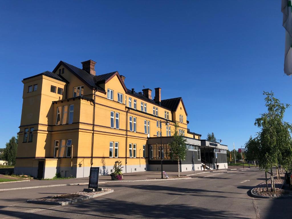 un grande edificio giallo sul lato di una strada di Orsa Järnvägshotell a Orsa