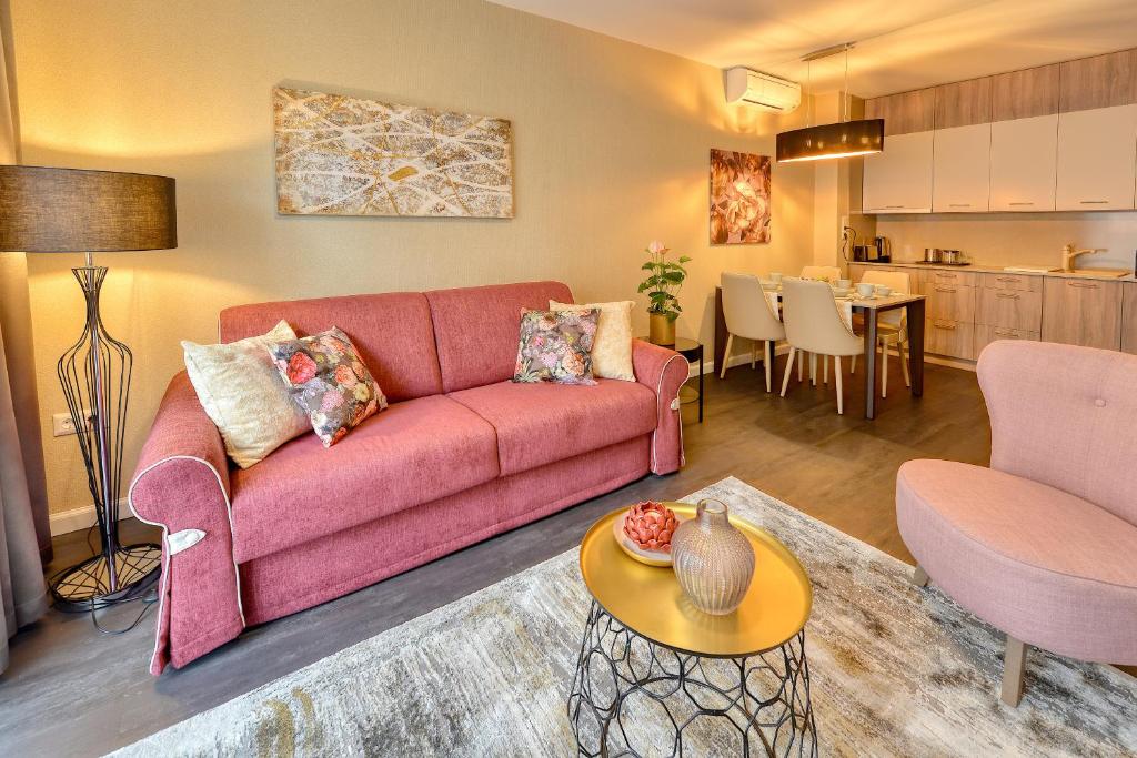 a living room with a pink couch and a kitchen at Club Luxury Apartman in Sárvár