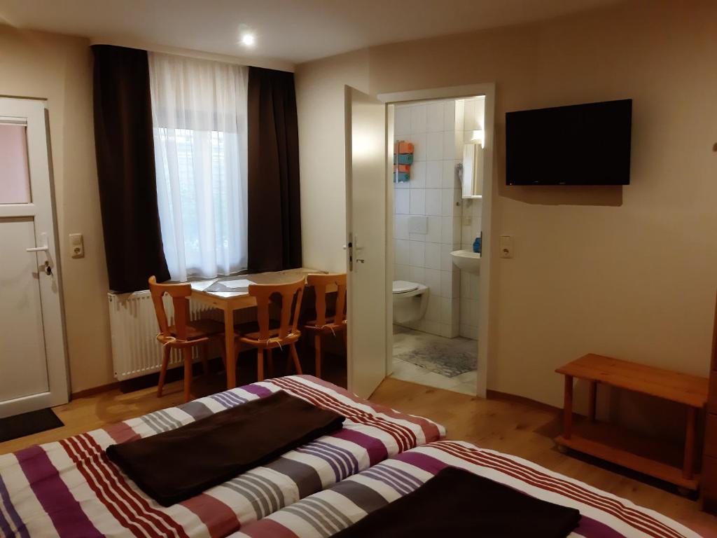 a bedroom with a bed and a table and a bathroom at Pension Lehmann in Radebeul