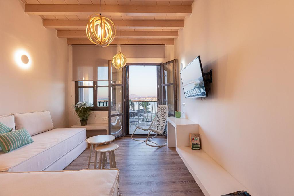 ein Wohnzimmer mit einem Sofa und einem TV in der Unterkunft V77 Seafront Suites in Rethymno