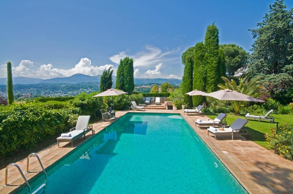 une piscine avec chaises et parasols dans l'établissement Le Mas du Chanoine, à Saint-Paul-de-Vence