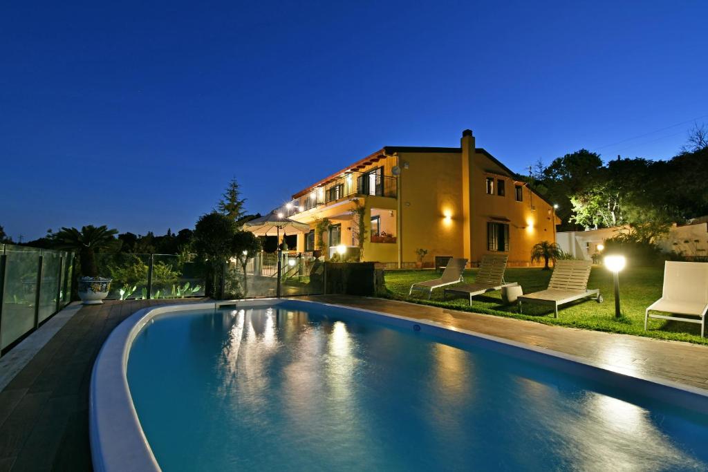 a swimming pool in front of a house at night at Bellavista Etna in Mascali