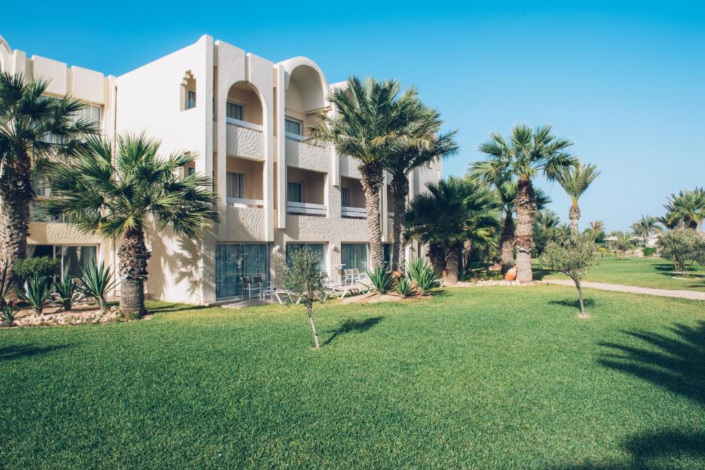 a large building with palm trees in front of it at Iberostar Waves Mehari Djerba in Taguermess