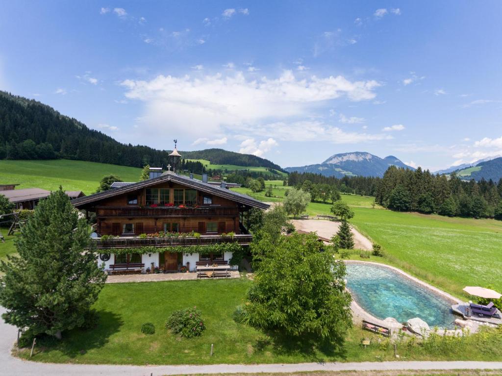 una casa en una colina con una piscina frente a ella en Weberhof Hopfgarten, en Hopfgarten im Brixental