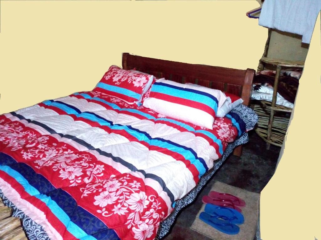a bed with colorful blankets and pillows in a room at Maverick Camp, Rondavels and Homestay in Nyandarua 