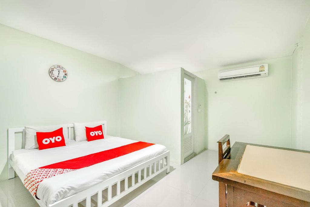 a white bedroom with a bed with red pillows at OYO 722 I Oun Inn in Nakhon Nayok