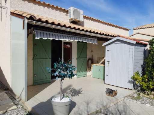 a cat sitting in front of a house at Pavillon Grazel GRUISSAN in Gruissan