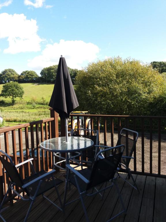 une table et des chaises sur une terrasse avec un parasol dans l'établissement Watercress Barns, à Sittingbourne