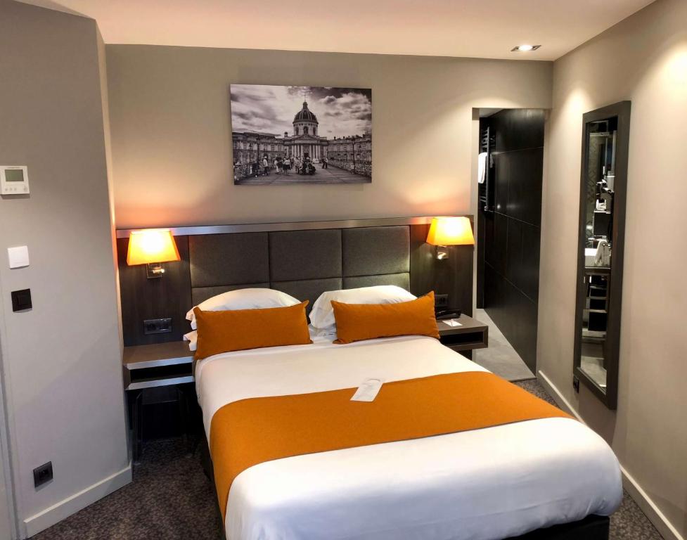 a hotel room with a large bed with orange pillows at Best Western Empire Elysees in Paris