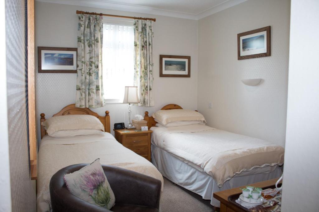 um quarto com 2 camas, uma cadeira e uma janela em Whitecroft B&B em Edinburgo