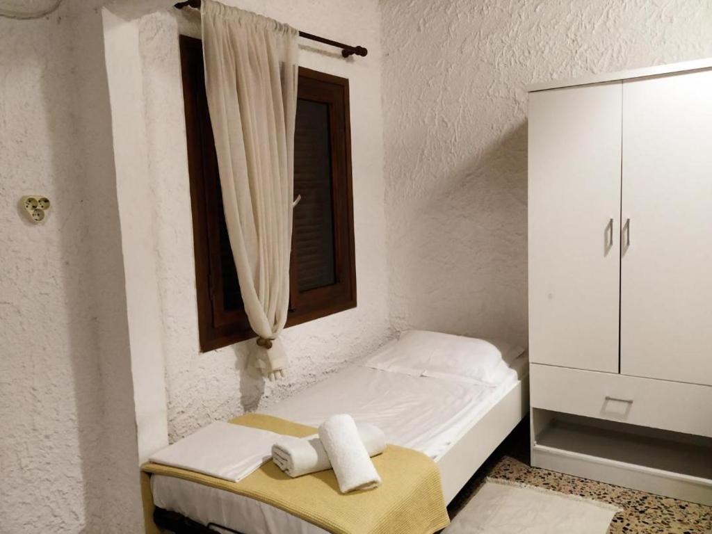 a white bedroom with a bed and a window at Dialiskari #2 in Limniónas